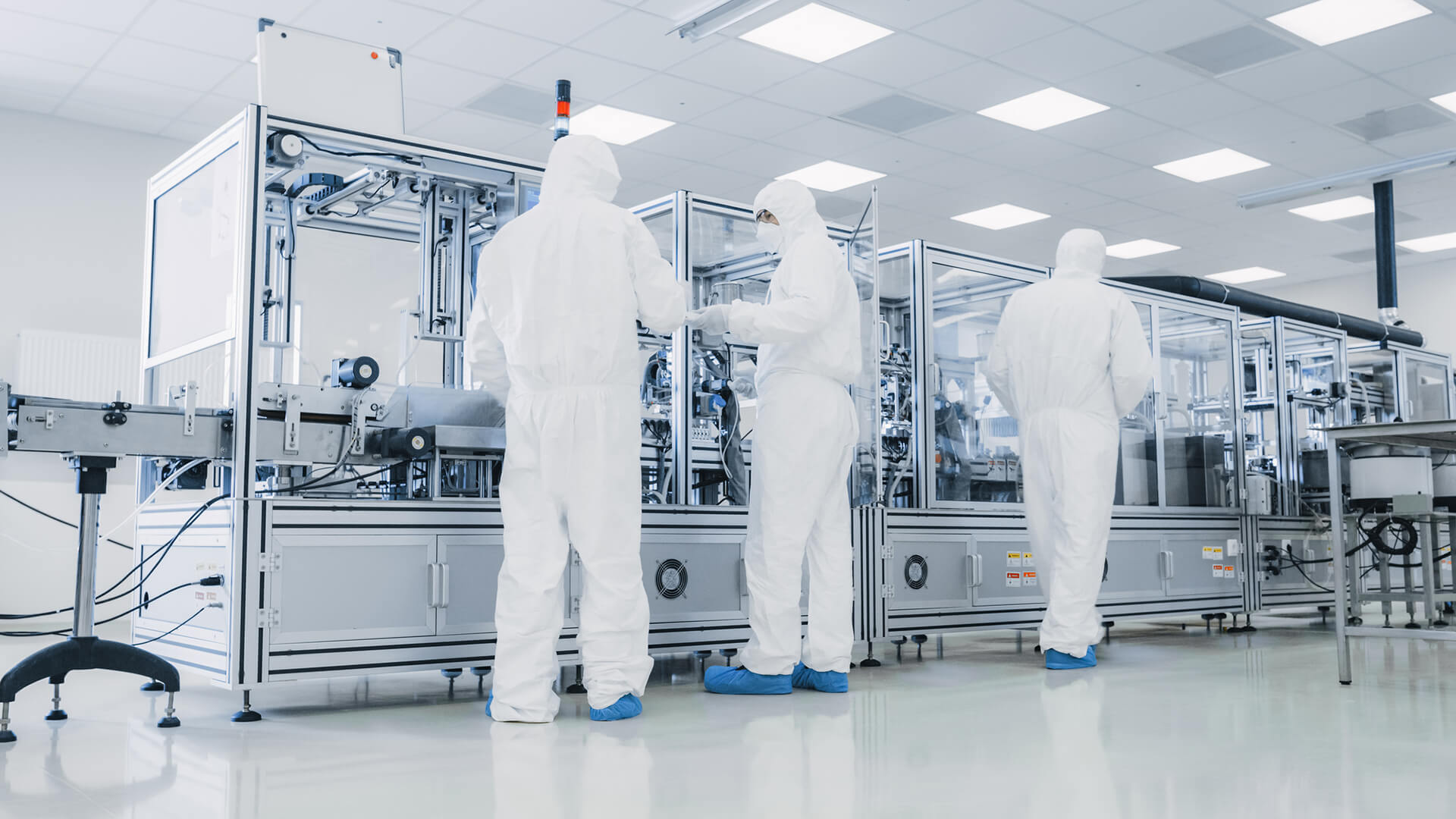 Employees in protective suits operate the production line in a clean room