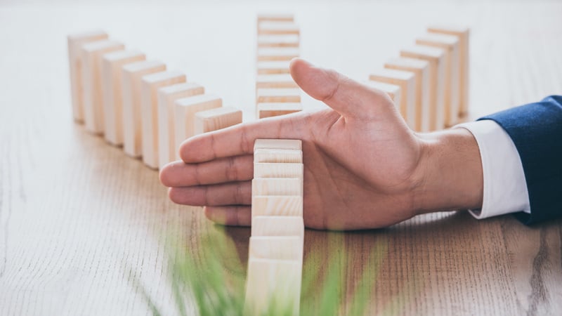 Hand stops a chain of dominoes from falling over